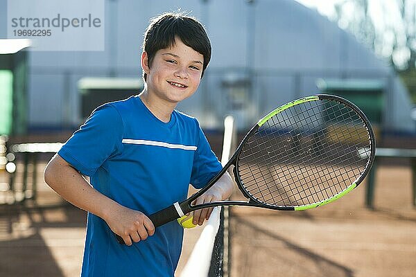Lächelndes Kind  das sich auf dem Tennisnetz ausruht