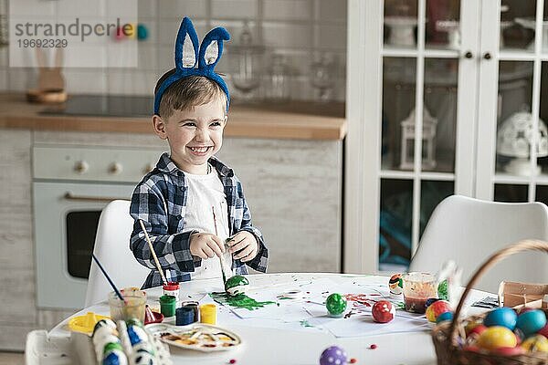 Porträt liebenswerter kleiner Junge malt Eier zu Ostern