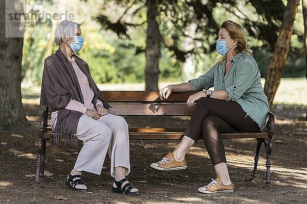 Zwei Frauen unterhalten sich mit medizinischen Masken im Freien vor einem Pflegeheim