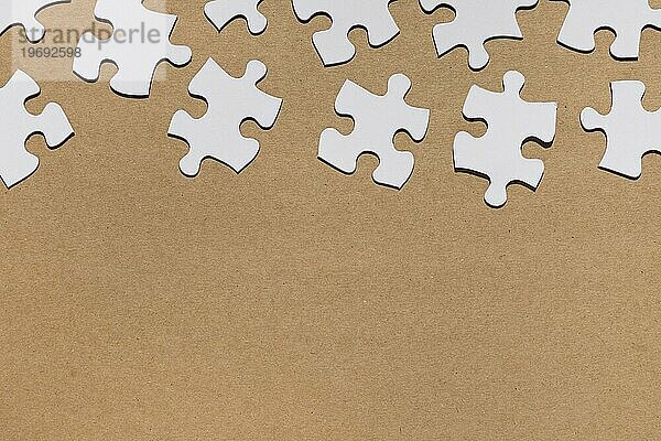 Draufsicht weiße Puzzlestücke braunes Papier strukturiert