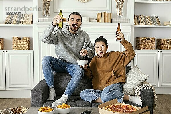 Pärchen trinkt Bier und ißt Snacks im Haus