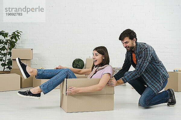 Ehemann schiebt seine Frau sitzend Karton