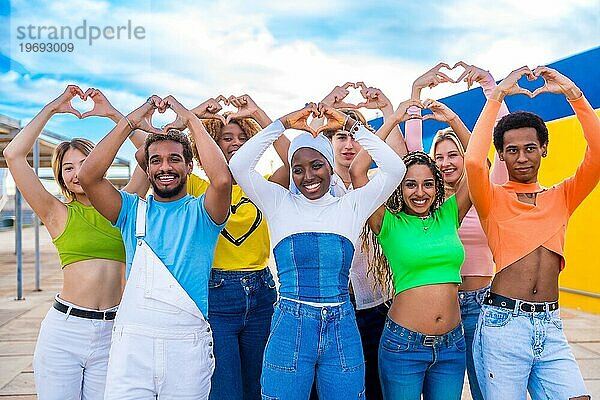 Multiethnische junge Menschen  die im Freien in einem städtischen Raum mit den Händen eine Herzform gestikulieren