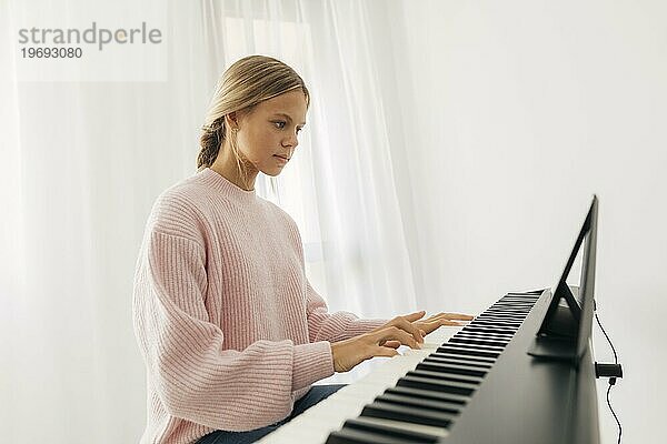 Junges Mädchen spielt zu Hause ein Tasteninstrument