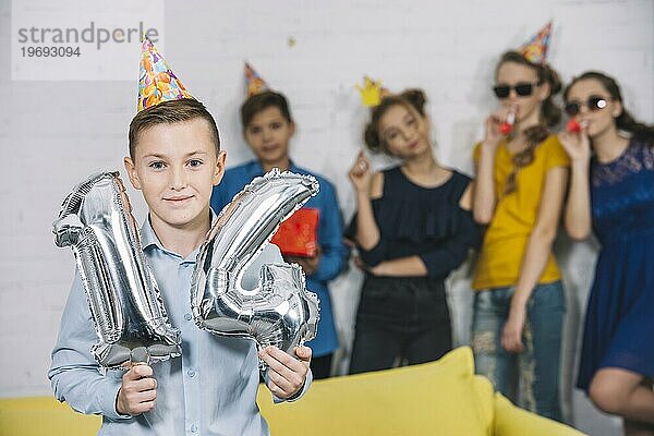 Geburtstagskind hält Zahl 14 Folie silberne Luftballons mit seinen Freunden stehen ihn