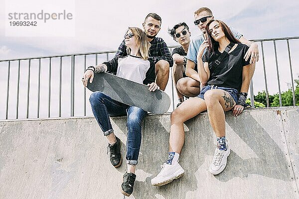 Gruppe Freunde sitzend am Geländer mit Skateboard