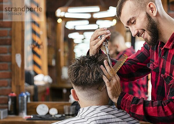 Gutaussehender Friseur beim Hipster Haarschnitt