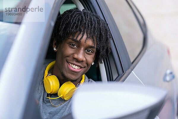 Nahaufnahme eines glücklichen afrikanischen jungen Mannes  der in einem Auto sitzt