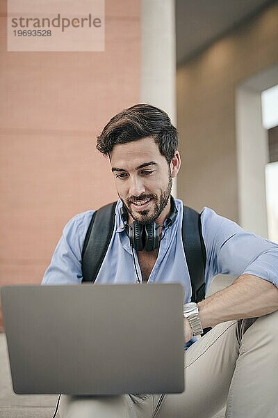 Nahaufnahme eines glücklichen männlichen Touristen  der einen Laptop benutzt