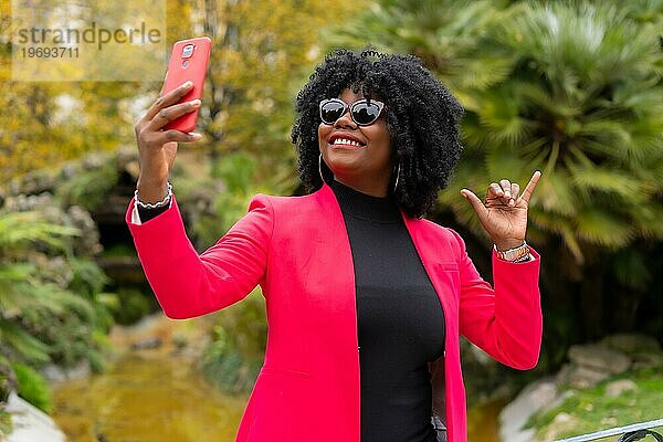 Porträt einer afroamerikanischen Geschäftsfrau in cooler Kleidung  die ein lustiges Selfie im Freien macht