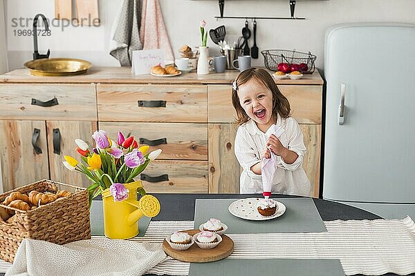 Glückliches kleines Mädchen macht Muffin