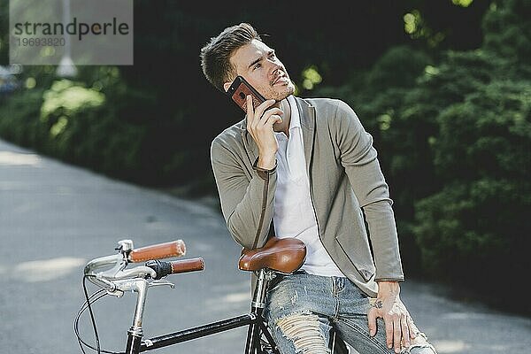 Mann sitzt auf dem Fahrrad und spricht mit dem Handy