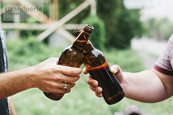 Close up Freund s Hand Toasting braun Bierflaschen im Freien