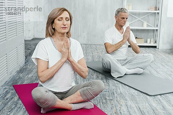 Konzentriertes Seniorenpaar beim Yoga zu Hause