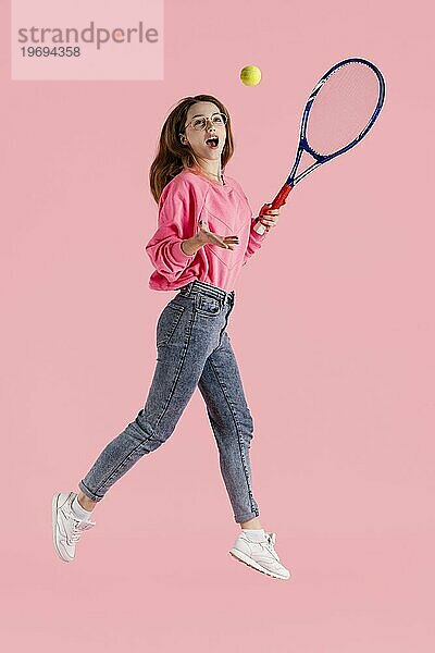 Portrait glückliche Frau mit Tennisschläger springend