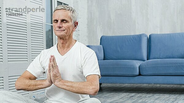 Meditierender älterer Mann mit betenden Händen