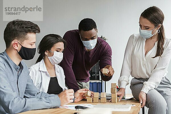 Kollegen  die sich während der Pandemie mit medizinischen Masken im Büro treffen