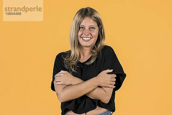 Vorderansicht lächelnde junge Frau umarmt sich selbst gelbe Oberfläche