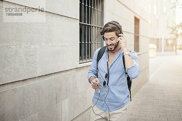 Glücklicher Mann  der auf dem Bürgersteig geht und Musik hört
