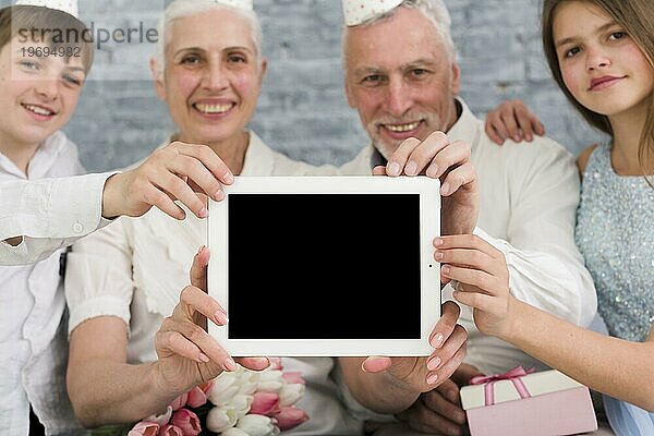 Glückliche Familie zeigt leeren Bildschirm digitales Tablet