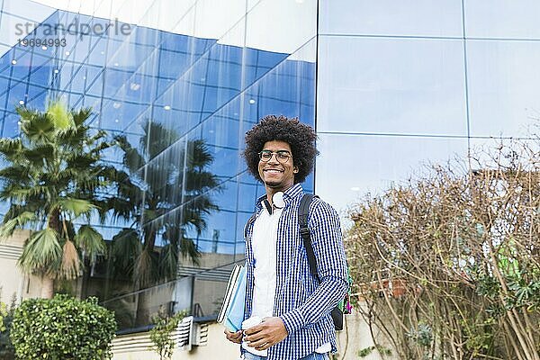 Porträt männlicher junger Student vor Universitätsgebäude stehend