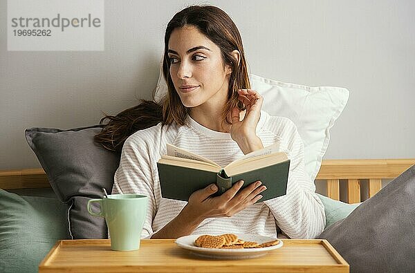 Vorderansicht Frau lesend beim Frühstück zu Hause