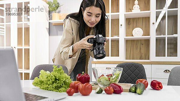 Weibliche Vloggerin zu Hause beim Fotografieren mit der Kamera