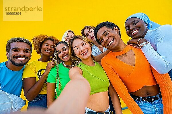 Nahaufnahme von multiethnischen Freunden  die ein Selfie neben einer gelben Stadtmauer machen