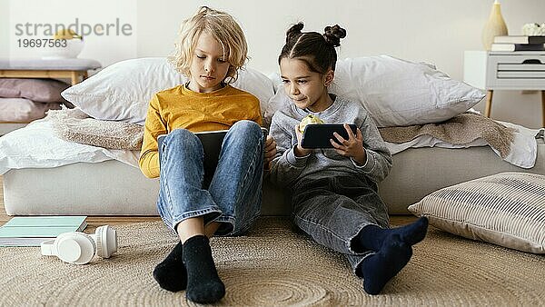 Geschwister spielen mit dem Handy Tablet