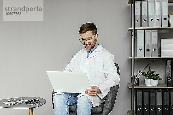 Medium shot smiley doctor working with laptop