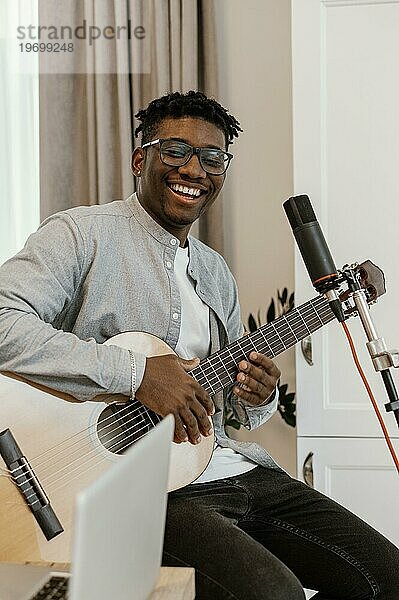 Smiley männlicher Musiker zu Hause Gitarre spielend und singend