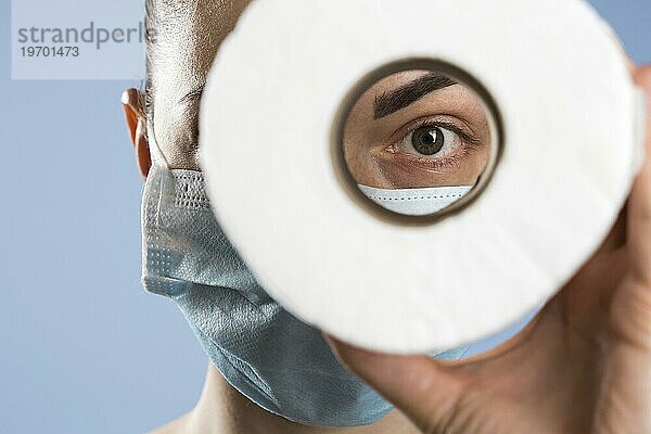 Vorderansicht Frau mit medizinischer Maske  die durch Toilettenpapier schaut