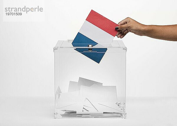 Person wirft Frankreichflagge Karte in Wahlurne