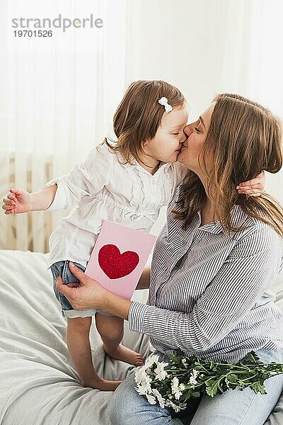 Tochter Mutter mit Grußkarte küssend