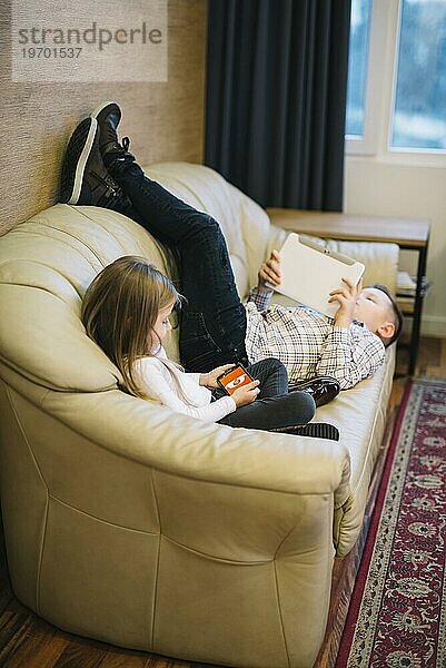 Close up Mädchen sitzt in der Nähe von Bruder suchen digitale Tablette Sofa