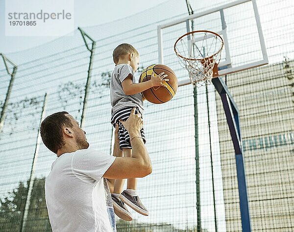 Glückliche monoparentale Familie beim Basketballspielen