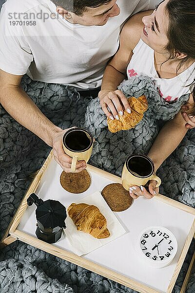 Ehepaar ißt Croissants mit Kaffee im Bett