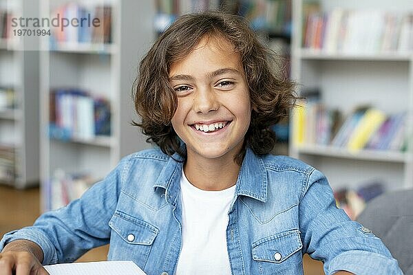 Junge lächelnd in der Bibliothek sitzend