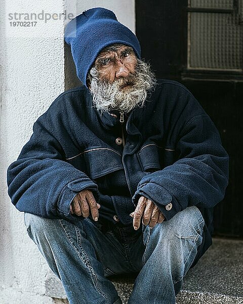 Vorderansicht Obdachloser mit Bart vor der Haustür