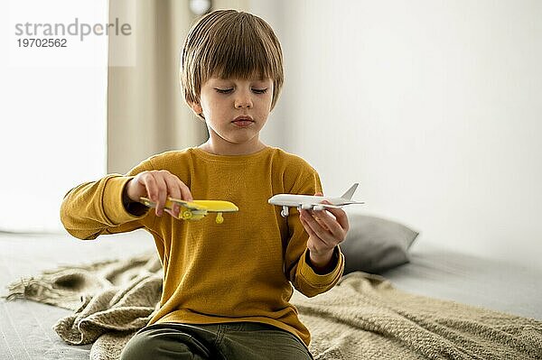 Vorderansicht Kind spielt mit Flugzeugfiguren