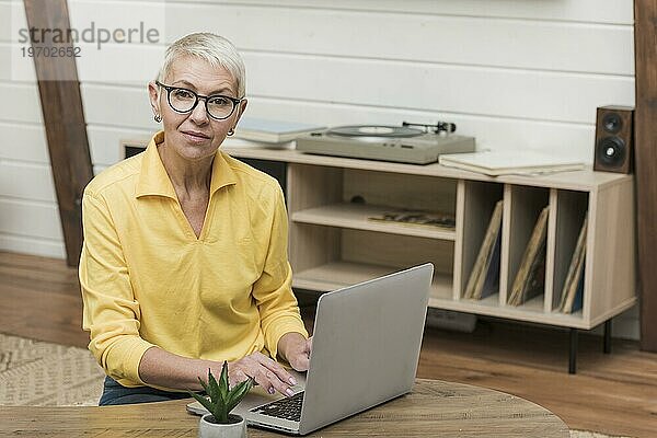 Vorderansicht ältere Frau  die durch das Internet auf ihren Laptop schaut