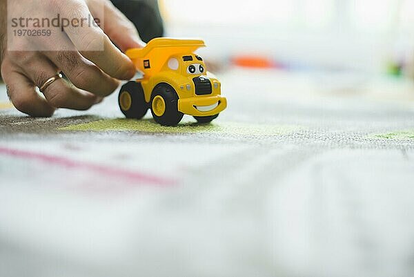 Nahaufnahme Hand mit gelbem Spielzeugauto