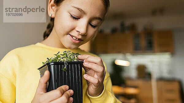 Kleines Mädchen zu Hause mit kleiner Pflanze