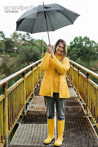 Frau auf Brücke mit Regenschirm