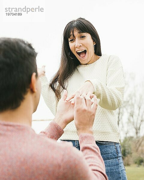 Junger Mann macht seiner aufgeregten Freundin einen Heiratsantrag