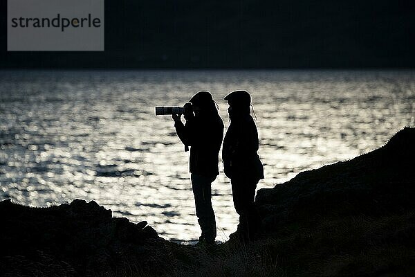 Silhouette  Tourist und Fotograf mit Kamera und langer Brennweite  Steingrímsfjörður  Westfjorde  Island  Europa