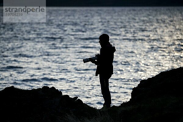 Silhouette  Fotograf mit Kamera und langer Brennweite  Steingrímsfjörður  Westfjorde  Island  Europa