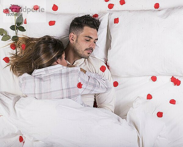 Junges Paar im Bett mit Rosenblättern