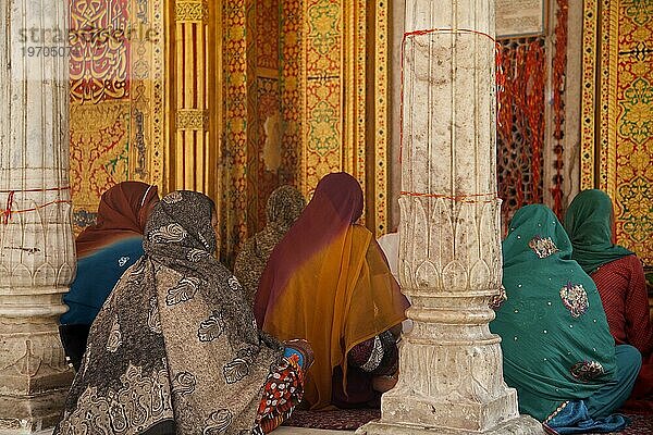 Muslimische Frauen mit bunten Kopftüchern und Saris beim Gebet am Nizam Ud Din Schrein in Delhi  Indien  Asien