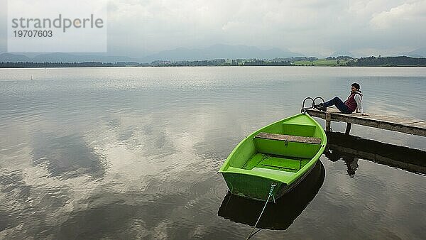 Frau 50+  Holzsteg  grünes Ruderboot  Hopfensee  Hopfen am See  bei Füssen  Ostallgäu  Allgäu  Bayern  Deutschland  Europa